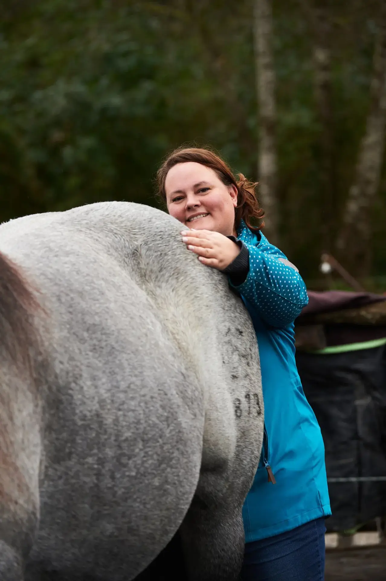Dorntherapie mit Christiane Hunkliner die hier hinter einem Pferd steht und den Kruppenbereich behandelt. Das Pferd ist nur teilweise zu sehen.